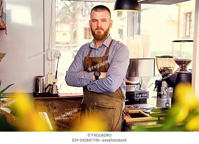 Portrait of bearded redheads seller in a small coffee house
