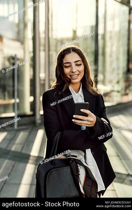 Smiling businesswoman checking cell phone