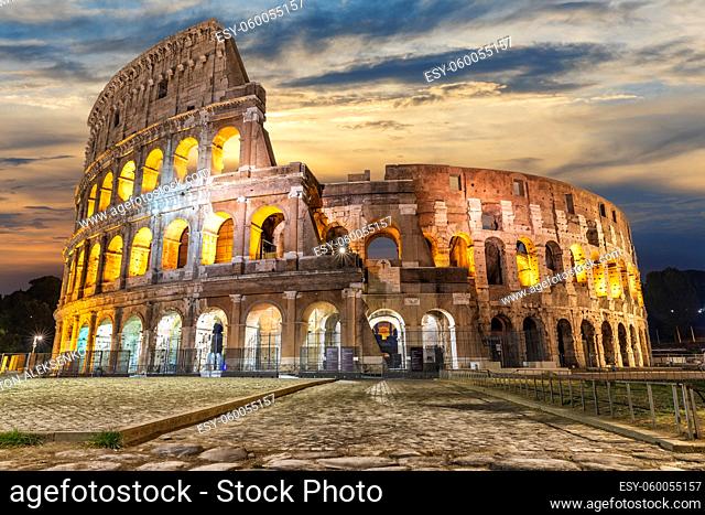 Illuminated Roman Coliseum under the clouds at sunrise, Italy