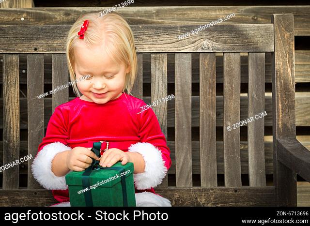 Adorable Little Girl Unwrapping Her Gift on a Bench Outside