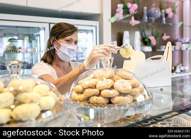 female bakery owner preparing an order and wearing a protective mask due to the corona virus pandemic