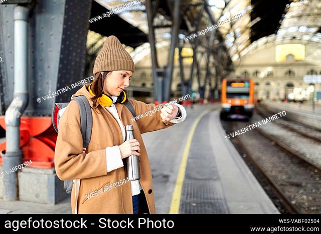 Young woman checking the time at the train station
