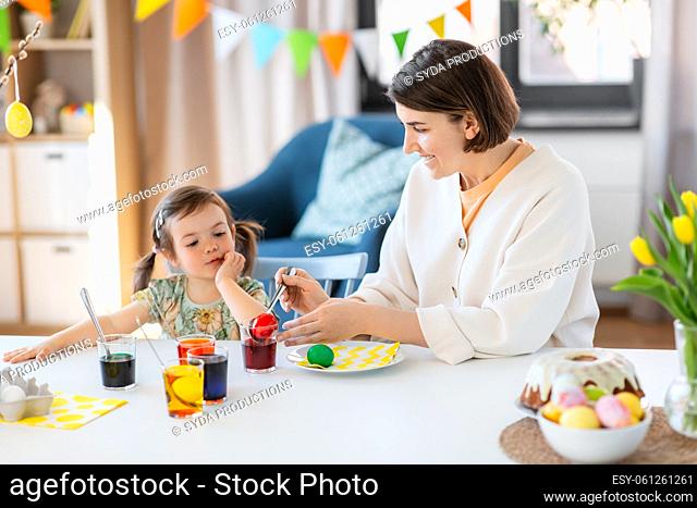 mother with child dyeing easter eggs at home