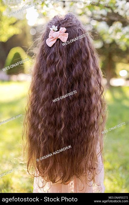 Girl with long wavy hair wearing pink bow