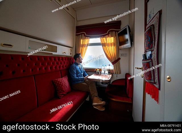 Trans-Siberian railway in winter, man sitting in train looking out of window, Russia