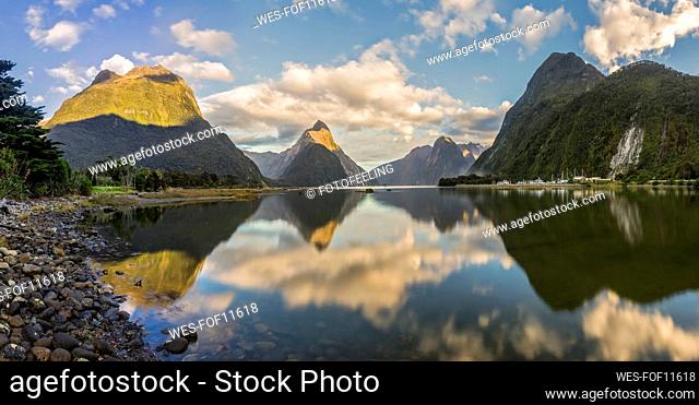 New Zealand, Scenic view of clouds and mountains reflecting on shiny surface of Milford Sound