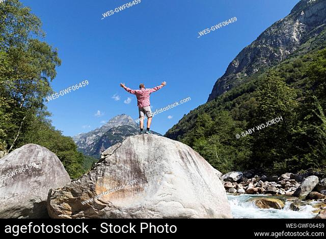 Man standing on rock at Verzasca river, Verzasca Valley, Ticino, Switzerland
