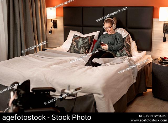 Happy woman using cell phone in bed
