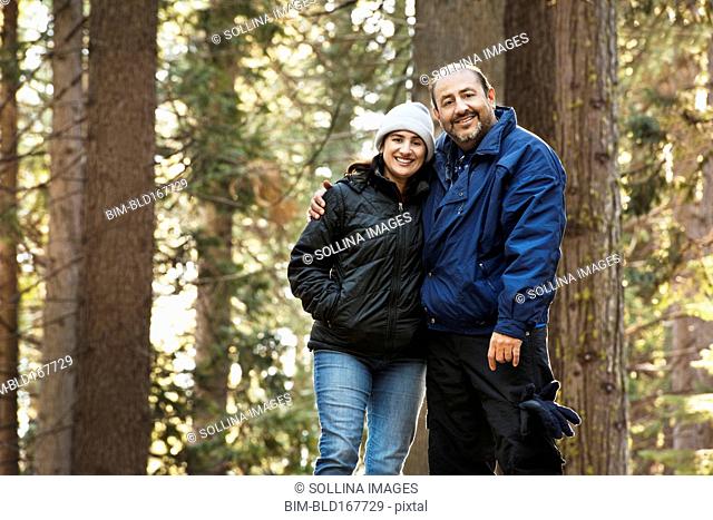 Hispanic couple hugging in forest