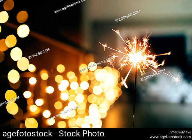 Sparklers on blurred christmas lights. Festive mood. High quality photo