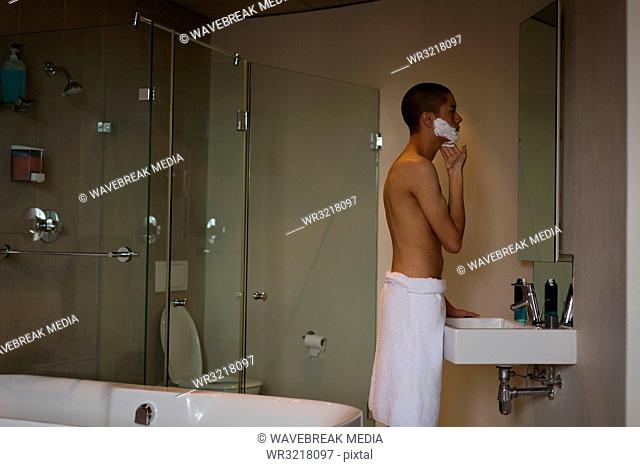Young man applying shaving cream on his face
