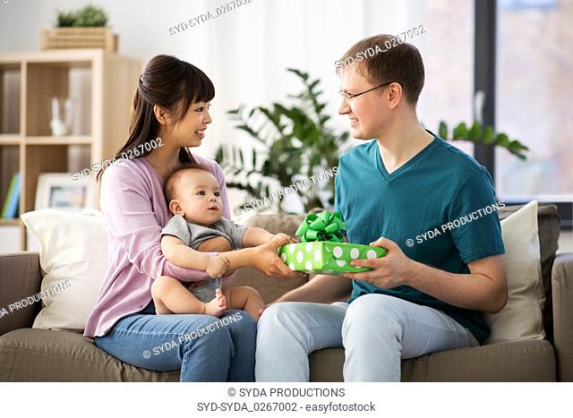 mother with baby giving birthday present to father