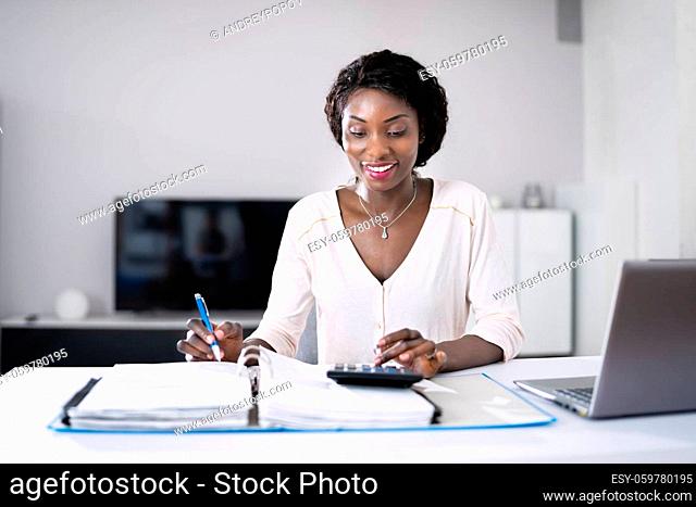 Happy Young African Woman Doing Taxes And Money Budget