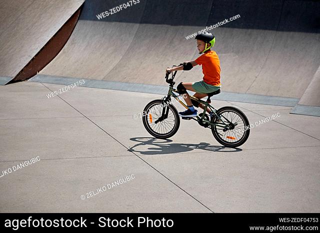 Boy riding BMX bike at skateboard park
