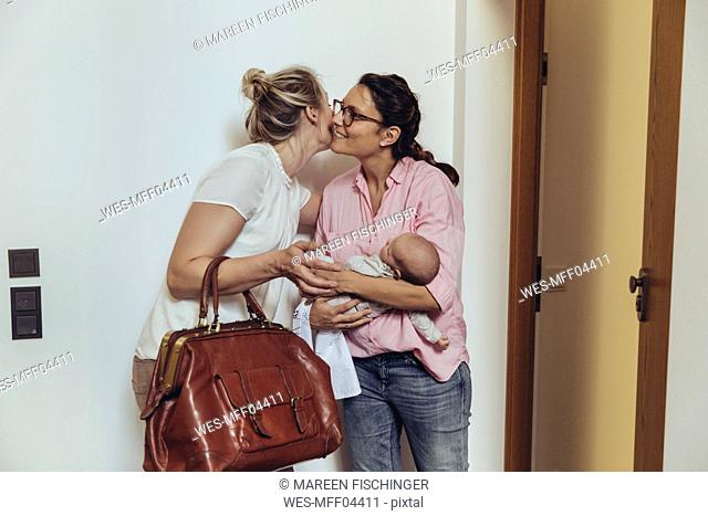 Woman greeting midwife at her homeƒ.s apartment door