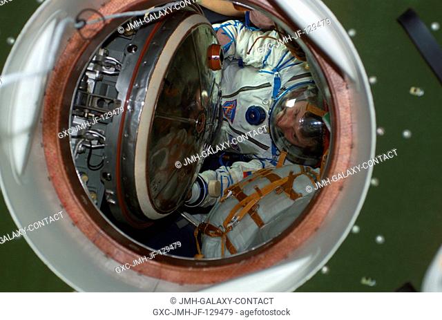 Astronaut Peggy A. Whitson, Expedition Five flight engineer, wearing a Russian Sokol suit, moves through a hatch in a Soyuz spacecraft that is docked to the...