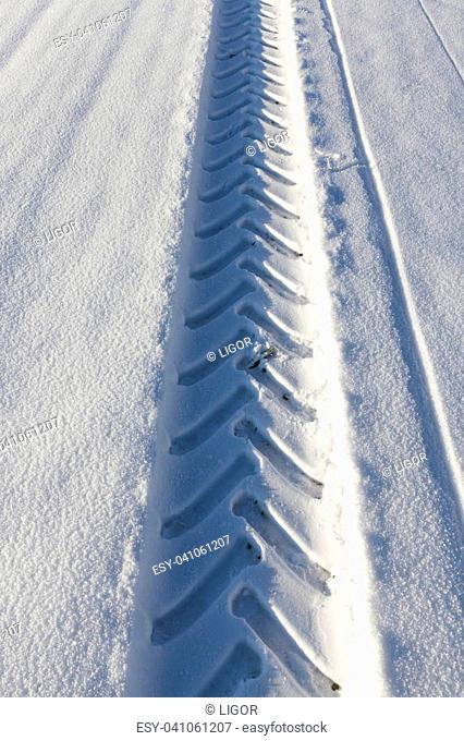 Track car wheel on the white real snow after snowfall. Winter photo close-up