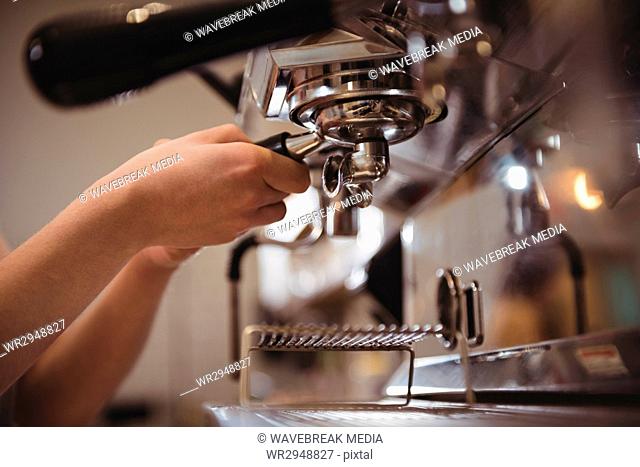 Barista fixing portafilter into coffee machine at cafe