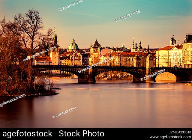Panorama of Prague at sunset, the golden colorful Vltava embankment and the Legion Bridge