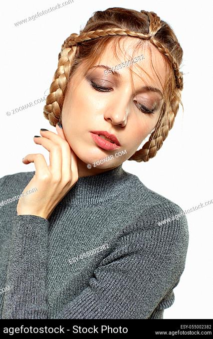 Portrait of beautiful young dark blonde woman. Female with creative braid hairdo on gray background. Girl with hand near face