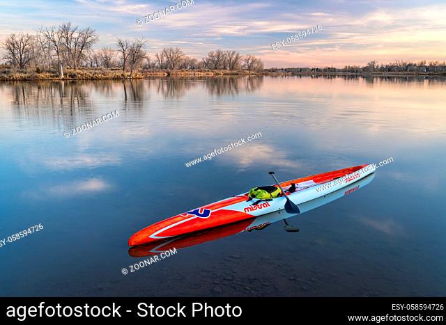 Fort Collins, CO, USA - March 6, 2020: A long racing flatwater stand up paddleboard (Mistral Stealth) on a calm lake at dusk after paddling workout - recreation
