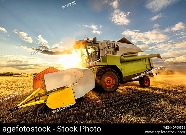 Back lit combine harvester on wheat field