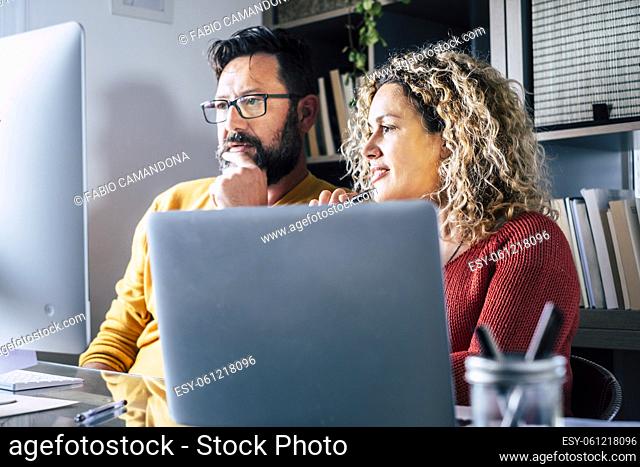 Man and woman team work together in couple at home with technology and online connection laptop computer and phone - smart working and remote workers concept...