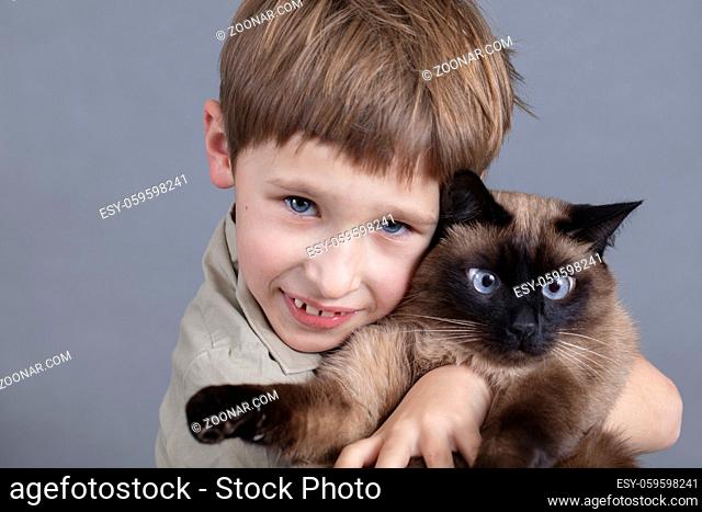 Portrait of a child with a cat. A boy with a Siamese cat