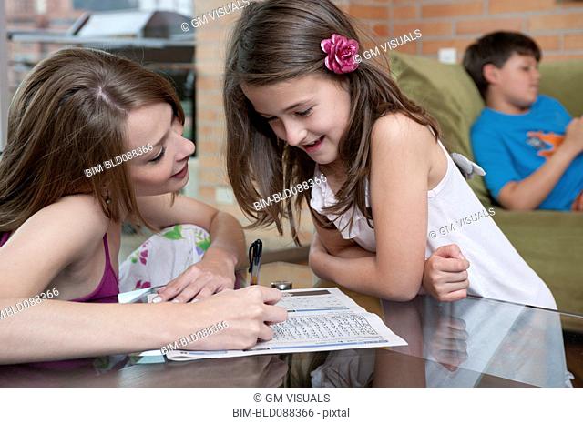 Hispanic mother and daughter looking at word puzzle