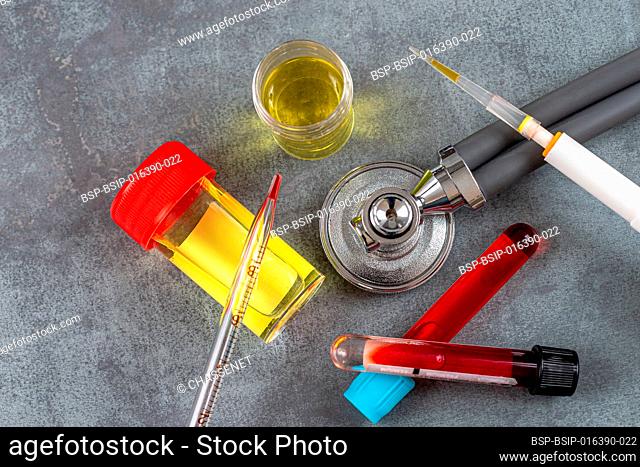 Stethoscope surrounded by blood tubes and urine bottles