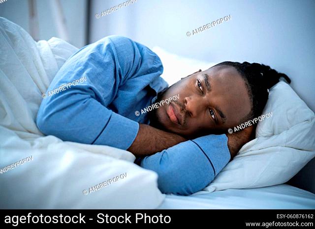 Young Man Suffering From Insomnia Lying In His Bed