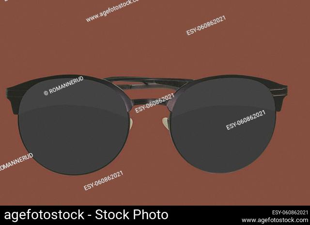 Sunglasses. Black sunglasses, close-up. Sun glasses. Old style sunglasses. Glasses with dark lenses. Vintage sun glasses on root beer color background