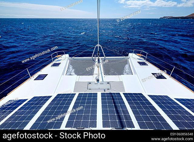 Luxury solar powered catamaran, fully sustainable and powered by solar energy, charging batteries aboard a sailboat, vessel in ocean waters, nobody