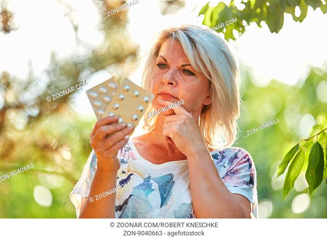Alte Frau mit Medikamenten in der Hand in der Natur