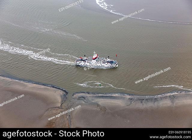 Dutch ferry boat at Wadden Sea navigating with low tide through small channels between sandbanks