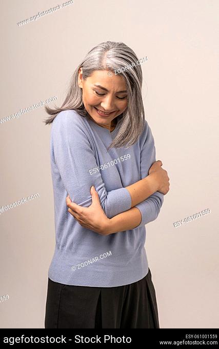 A Cute White-Haired Mongolian Woman on a White Background. The Woman s Gaze is Lowered. Embracing Herself She is Embarrassed by Something