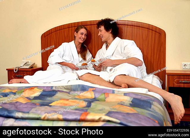Happy young family with breakfast lies in the bed at home
