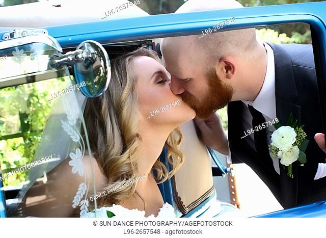 bride getting out of blue car & groom kissing her - shot through the window