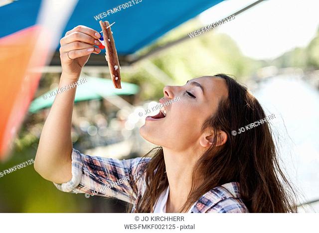 Netherlands, Amsterdam, young woman eating matjes herring