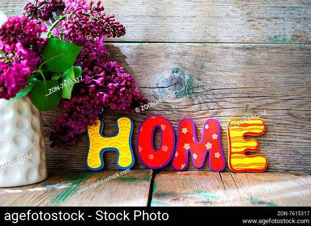 Lilac flowers in a pot and HOME letters on the wooden table