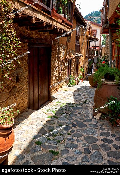 The view of the narrow stone paved sade street of the old Kakopetria lined by flowers in the pots. Nicosia District. Cyprus