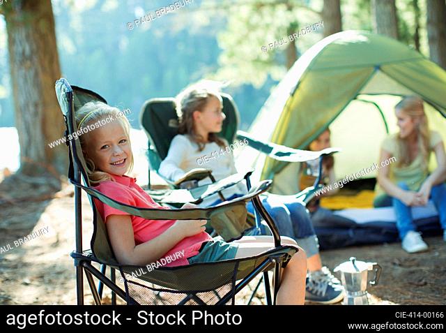 Smiling girl sitting in chair at campsite