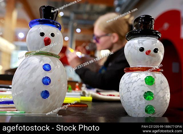 05 December 2023, Saxony-Anhalt, Derenburg: Two hand-blown snowmen stand on a work table where glassblower Miriam Hertel is making glass figurines