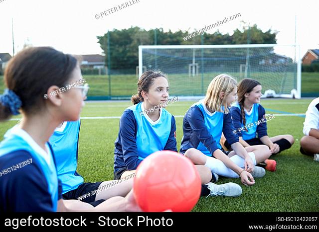 UK, Female soccer team sitting in field during training