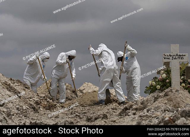 20 April 2020, Mexico, Tijuana: Workers in protective suits shoveling earth at a funeral during the Covid 19 pandemic. Covid 19 victims are buried in the State...