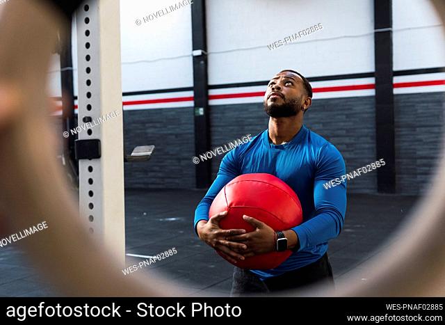 Athlete looking up holding medicine ball in gym