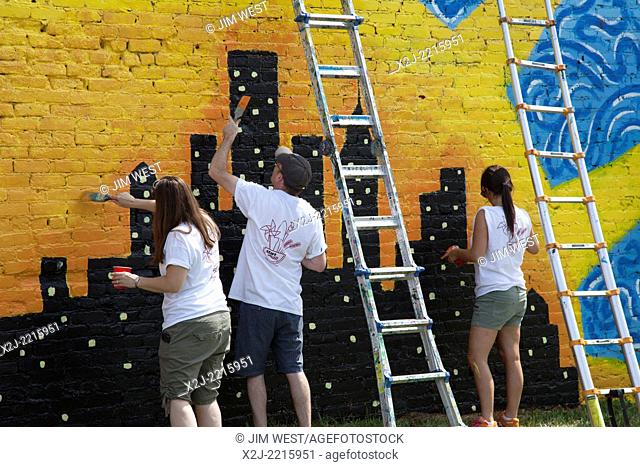 Detroit, Michigan - Volunteers from The Mars Agency paint a mural on a vacant building. They were working through Summer in the City