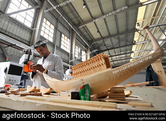 13 April 2021, Egypt, Obour City: A craftsman works on creating a miniature model of the ancient Egyptian Khufu Ship, at Konouz factory