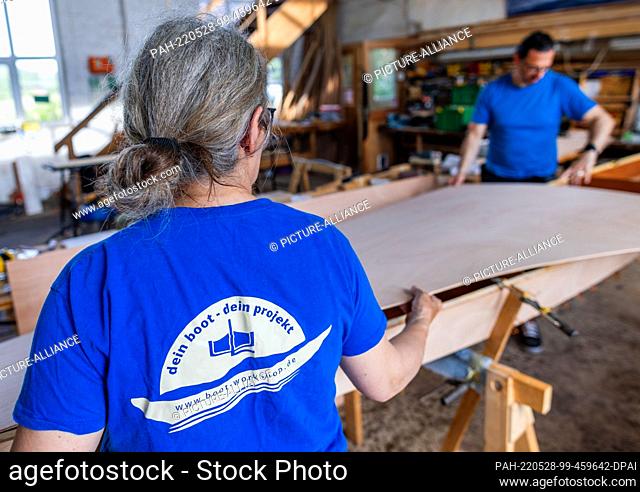 19 May 2022, Mecklenburg-Western Pomerania, Peenemünde: Together with Ursula Latus, participants of a boat-building workshop work on different wooden boat...
