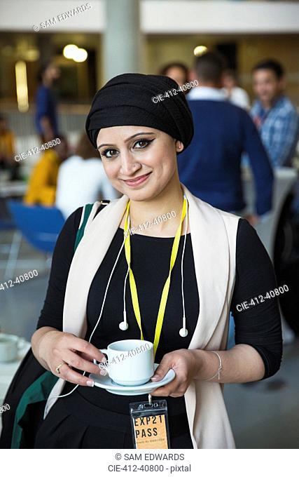 Portrait smiling, confident businesswoman in headscarf drinking coffee at conference